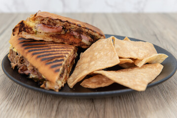 Grilled cubana sandwich hot off the press and served  with a side of chips.
