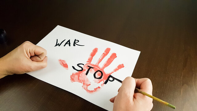 a person writes stop war on white paper. bloody hand palm print