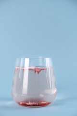 Collagen powder in a glass of water. Superfood additives. Skin care. Blue background.