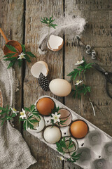 Happy Easter! Easter rustic still life. Natural easter eggs, blooming spring flowers, burlap and spoon  flat lay on rural wooden table. Simple stylish festive decoration on table.