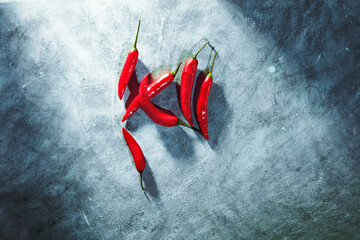 Red chilli peppers laying on rustic concrete background. Spicy ingredient on textured cement surface.