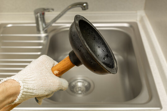 a hand in a glove holds a vantus on the background of a sink