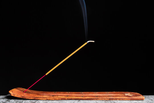 Side view of incense stick stands on a wooden stand isolated on a black background