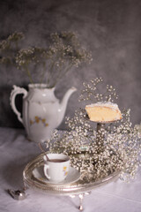 white still life with cheesecake and gypsophila and cup of tea, light and airy