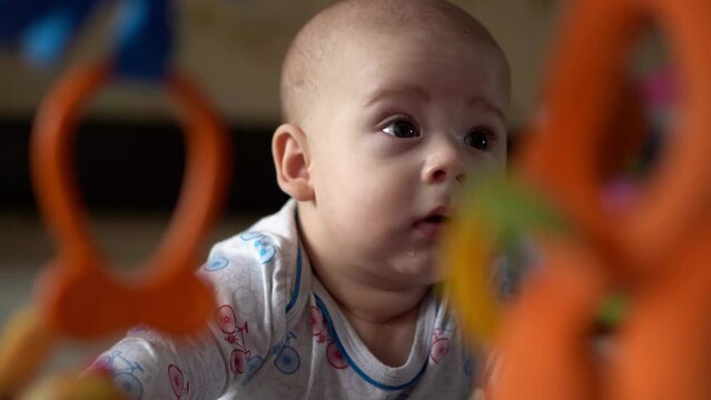 Newborn Active Baby Cute Smiling Teethless Face Portrait Early Days On Stomach Developing Neck Control. 5 Months Child In Playpen Gnaws Toys Look At Camera. Infant, Childbirth, Beginning Concept