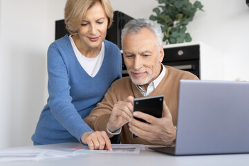 Senior couple calculating expenses in modern kitchen