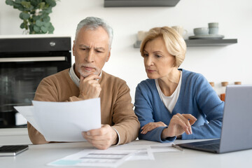 Elderly married couple looking at documents carefully