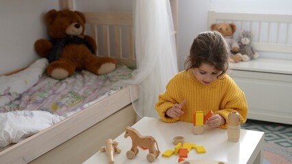 Caucasian girl playing with a wooden set of child development building blocks. Toys made of wood and natural and eco-friendly materials.