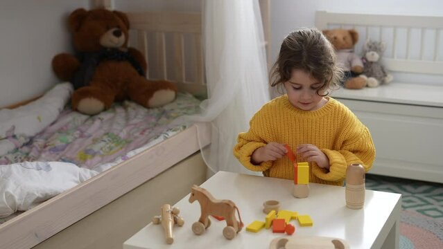 Caucasian girl playing with a wooden set of child development building blocks. Toys made of wood and natural and eco-friendly materials.