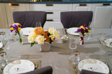 served dining table with utensils and flowers in the dining room. 