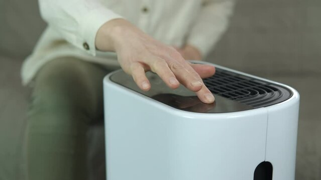 Air purifier in the smart home. A female use an air purifier in her smart home to clean the air.