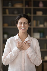 Vertical image joyful sincere millennial beautiful Hispanic woman with folded hands on heart...