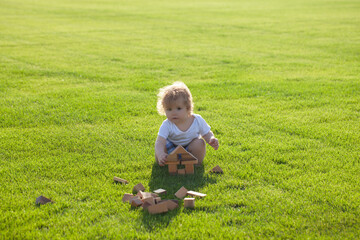 Naklejka na ściany i meble Little baby playing in nature on the green grass. Kids playing. Baby and summer sunny summer.