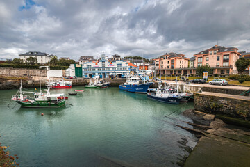 Fototapeta premium Picturesque port area of Puerto de Vega town in Asturias, Spain with beautiful blue waters and fishing boats.