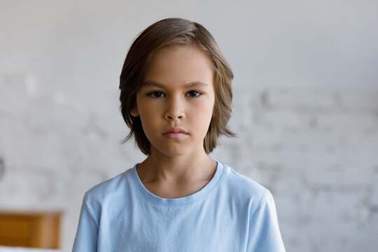 Serious Sulky Handsome Pre-teen 10s Boy Pose Alone In Living Room Staring At Camera Looks Gloomy, Head Shot. Adolescence, Difficult Personality, Bad Temper, Young Generation Z Child Portrait Concept