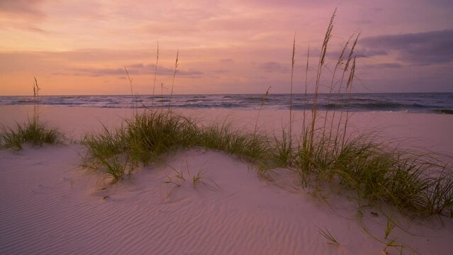 Calm sunrise and soft golden light over blue ocean and white sandy beach 