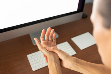 woman suppering from carpal tunnel, syndrome holding  touching her hand while working with laptop...