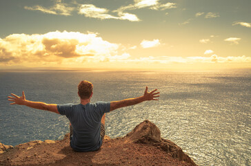 Man with open arms facing the sunrise, feeling happy at peace in nature 