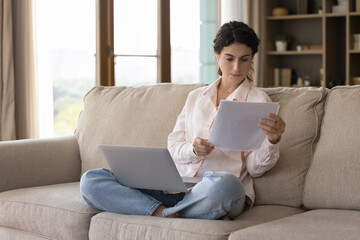 Focused millennial attractive Hispanic woman analyzing financial paper document or bank mortgage...