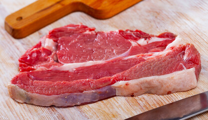 Raw juicy boned steak cut off beef sirloin ready for cooking on wooden table