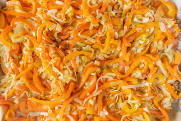 Fried onions, carrots sauteed, laid out on a baking sheet, top view. Preparation for a restaurant.