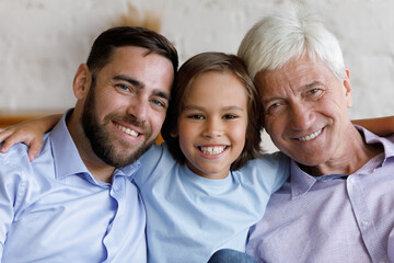 Handsome three gen, multi generational men relatives, head shot portrait. Little boy hugging older...
