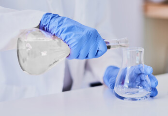 Discovering chemical reactions. Cropped shot of a scientist mixing chemicals in beakers while standing in a laboratory.