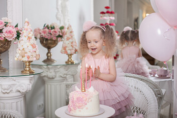 cute little girl blows out candles on a birthday cake 