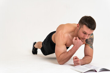 Bodybuilder reads the book on a white background isolated at the bottom of his head on his hands...