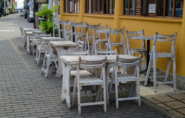 Empty wooden chairs and tables outside the restaurant in the morning, quiet and calm cobblestone Streets in Galle fort.