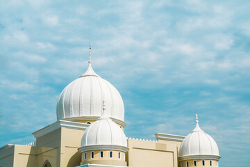 Cloudy clear blue sky over a mosque. Islamic praying building. Crescent on white covered dome and...