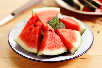 Fresh red watermelon slices in white plate on wooden background.