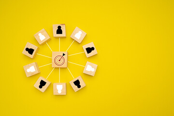 Wooden cubes with people icons focus on the goal over a yellow background - obrazy, fototapety, plakaty