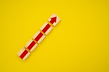 Fototapeta na wymiar Wooden blocks with red arrow up over a yellow background. Business growth concept