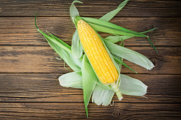 Fresh corn on the cob on a rustic wooden table - top view