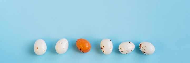 Easter minimal composition with multicolored eggs on the blue background. Easter concept. Copy space, flat lay. Banner.