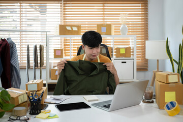 Asian man holding cloth to present product via live streaming online.