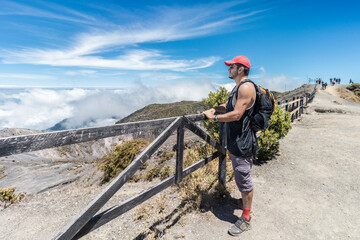 tourist with backpack observing from the wooden barrier and the landscape in the Irazu Volcano...