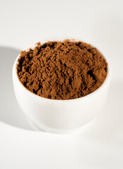 Cocoa powder in white bowl оn white background.