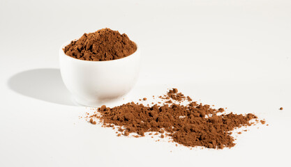 Cocoa powder in white bowl оn white background.