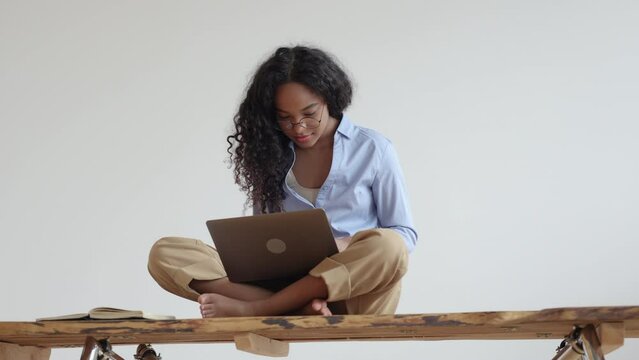 Woman student or freelancer working with laptop and daydreaming, sitting on desk at home spbi. 4k video Front view of young African amrican female looks at computer screen and works or studies