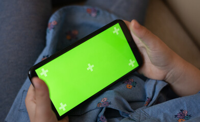 selective focus, Hands of child hold horizontally phone with green screen and play. kid talking online. Person study new technology, work online, communication from home