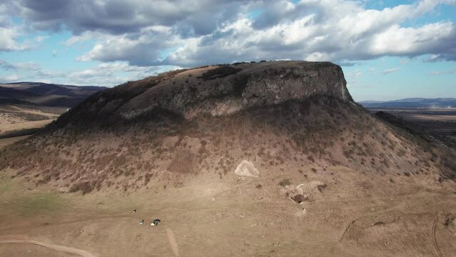 Aerial, low angle shot of a cliff standing out in the Romanian landscape.