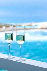 Two champagne glass on hotel room with beautiful azure ocean view in tropical country.