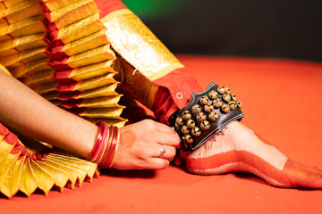 Close up shot, Bharatnatyam dancer removing music anklets or ghungroo khatak on stage after dancing - concept of classical dancer, Indian tradition and hobbyist
