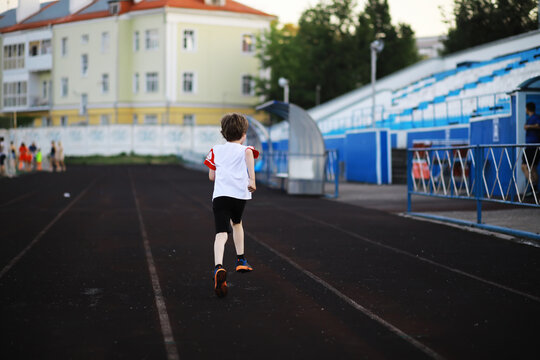 The child goes in for sports at the stadium. The boy is training before playing football.