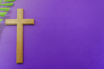 Cross and palm leaves on purple background. Lent season concept.