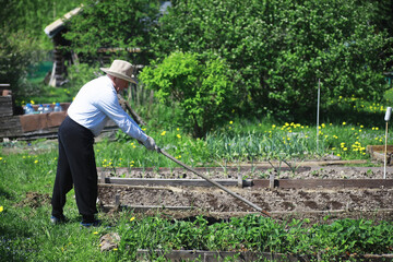 The farmer is digging a garden. A man with a harvester plows the garden. The gray-haired grandfather mows the garden.