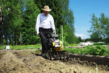 The farmer is digging a garden. A man with a harvester plows the garden. The gray-haired grandfather mows the garden.