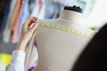 Woman dressmaker measuring on mannequin back for further sewing